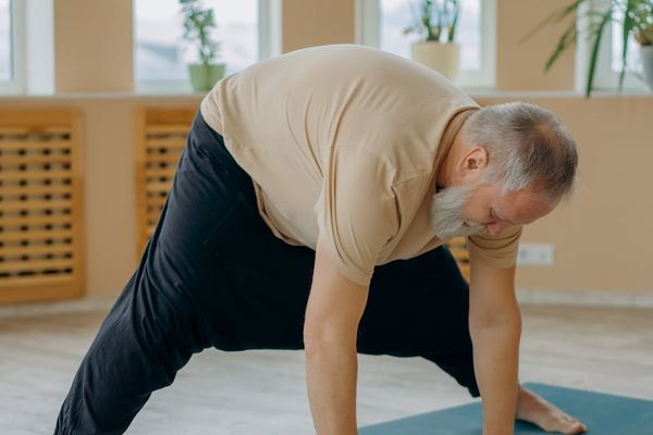 Man stretching on a yoga mat in a calm, focused environment with soft lighting.